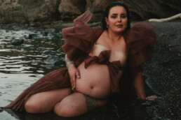 Photographe grossesse Cannes - femme enceinte assise bord de l'eau avec robe en tulle marron