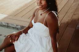 fashion photographer sint maarten dark skin woman sitting in pool deck with warm natural light